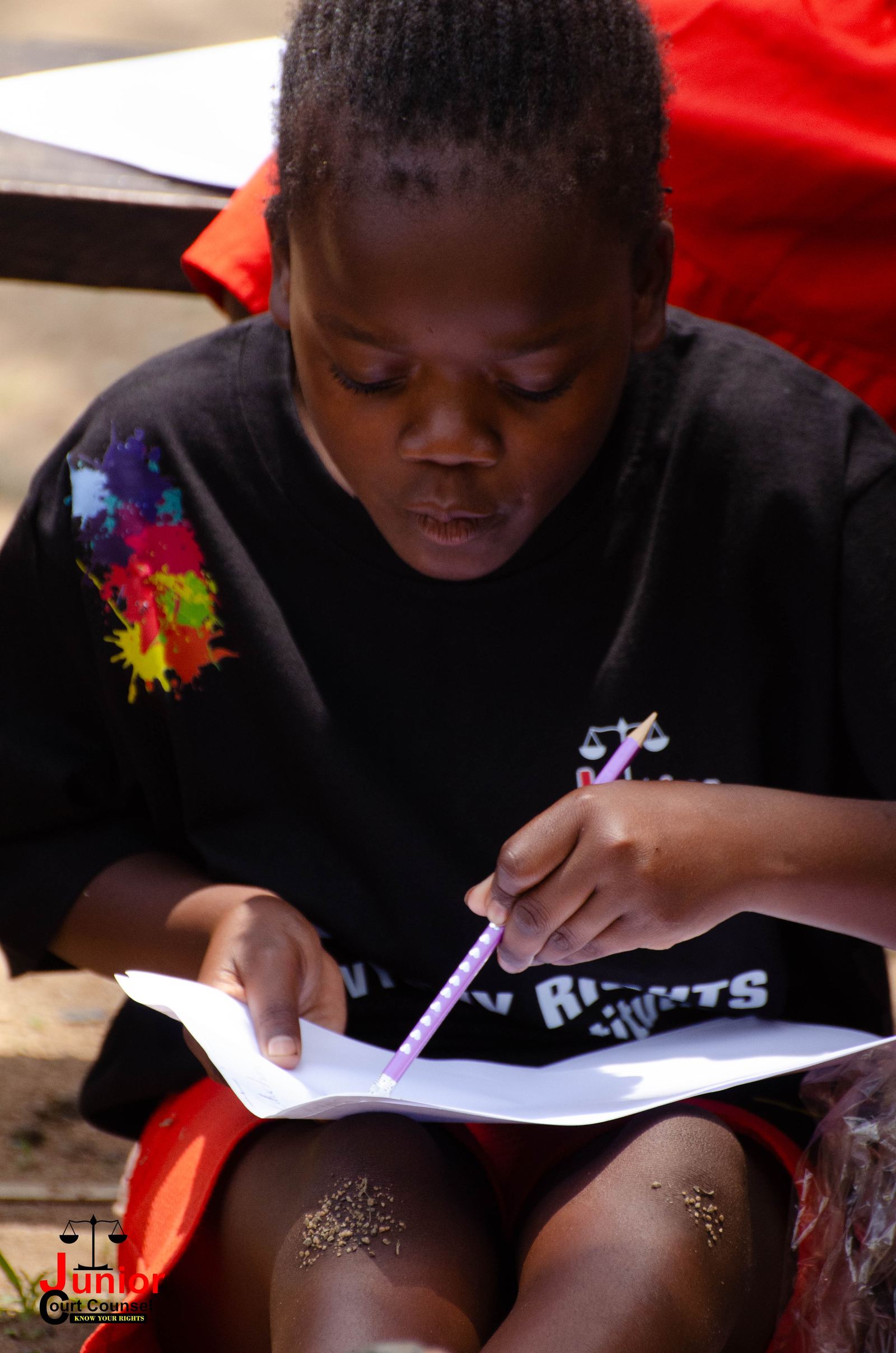 Close-up of a child carefully writing on paper during a JCC session