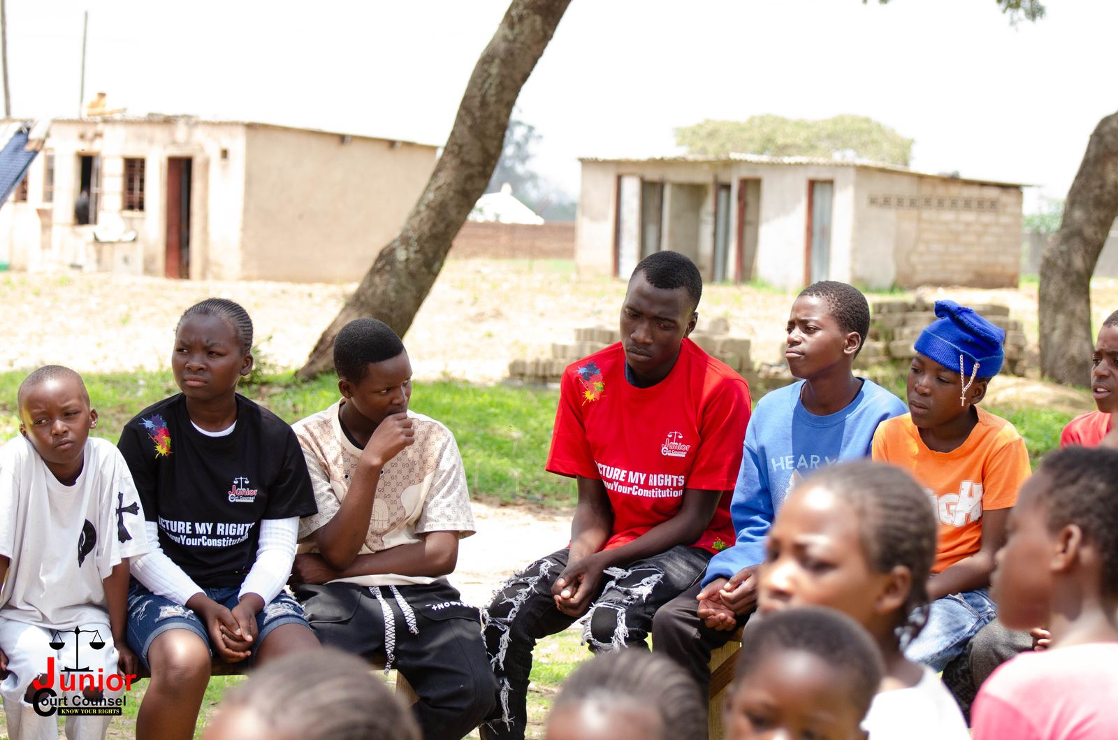 A circle of teenagers sitting together and listening attentively during a JCC discussion session outdoors